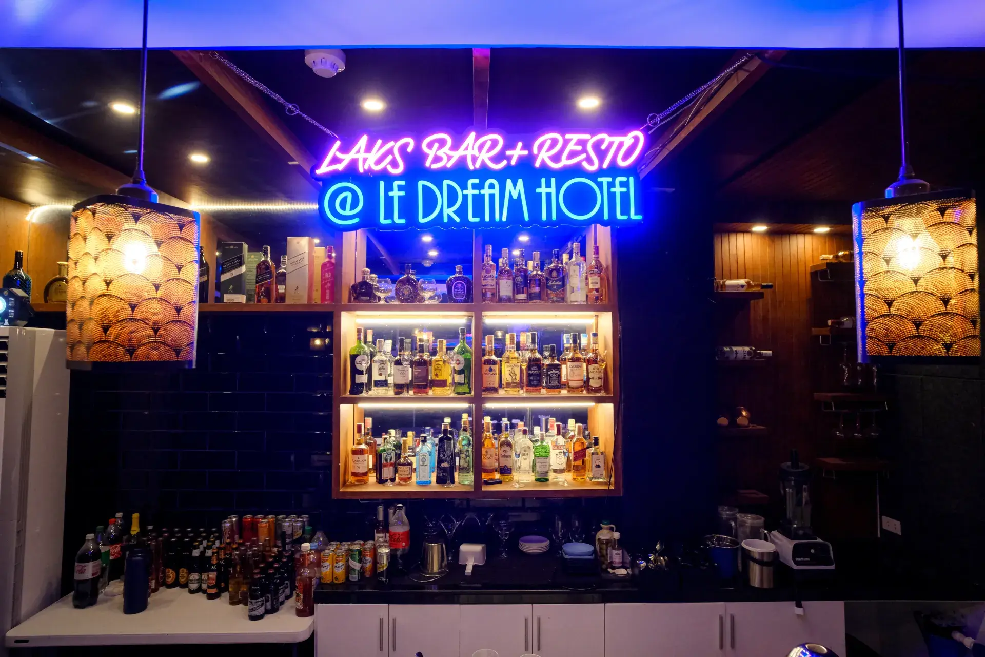 LAK's neon sign over the bar's lit shelves of bottles